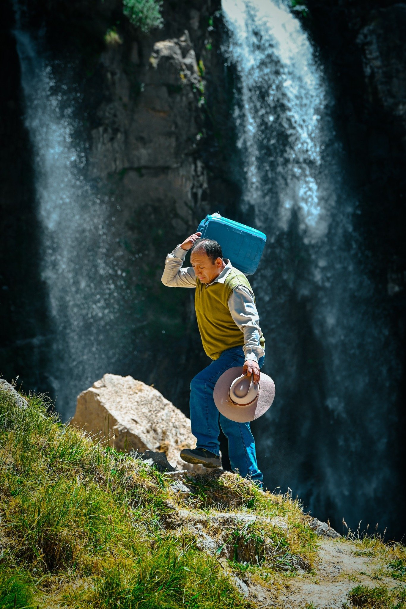 Agricultor cargando un bidón de agua junto a una catarata